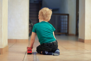 child with backturned playing with truck possibly in need of autism testing
