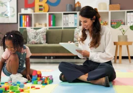 A kid and a doctor with clipboard, blocks and happy for evaluation, assessment or writing on floor.
